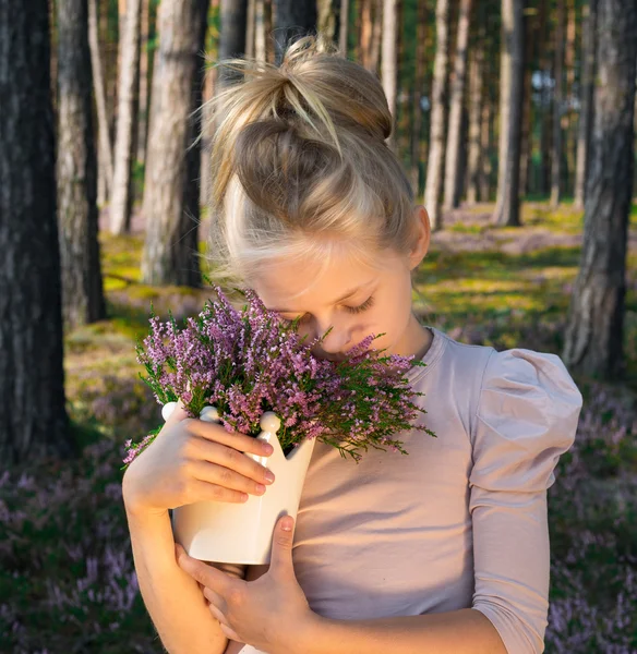 Hermosa chica en el bosque sosteniendo en un jarrón con brezo . — Foto de Stock