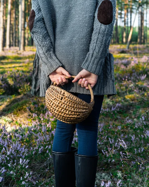 Дівчина стоїть до камери в лісі і тримає кошик . — стокове фото