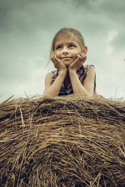 国家概念-年轻漂亮的女孩躺在干草堆上风暴云 — 图库照片