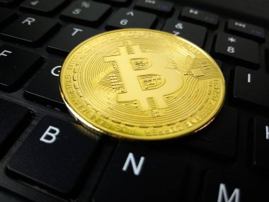 Bilgisayar klavyesine yerleştirilmiş altın bir Bitcoin 'in yakın plan fotoğrafı şifreli para, dijital para birimi, engelleme zinciri teknolojisi, online yatırım ve fintech konseptini sembolize ediyor. Seçici odak ile makro çekim.