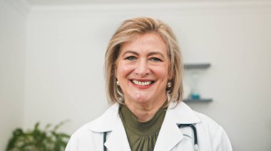 Steteskopla beyaz önlüklü, sıcak, gülümseyen bir kadın doktor, profesyonellik, bakım ve temiz bir klinik ortama güvenme sağlıyor..