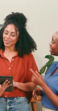 İki mutlu, çeşitli kadın dijital tablete bakarak verimli bir tartışmaya giriyorlar. Gülümser, işbirliği yapar, takım çalışmasını somutlaştırır ve modern bir çalışma alanında başarıyı paylaşırlar..