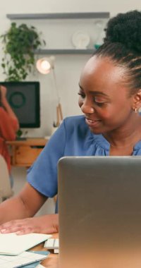 Neşeli bir kadın işine dikkatle odaklanır, bir dizüstü bilgisayar kullanır ve parlak, modern bir ofis alanında notlar alır. Mutlu tavrı, üretken ve çekici bir mesleki çevreye işaret ediyor..