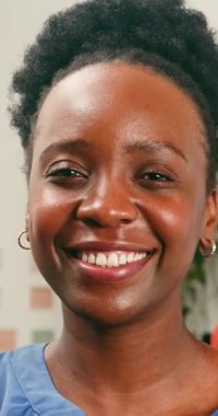 Güzel bir yakın plan portresi. Neşeli, genç, siyah bir kadın. Işıl ışıl gülümseyen, doğrudan kameraya bakan. Neşeli ifadesi mutluluğu ve sıcaklığı iletir..