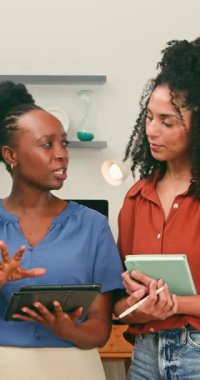 İki profesyonel iş kadını, parlak ve modern bir ofiste dijital tabletlerle ilgili proje detaylarını gözden geçiriyorlar. Odaklanmış etkileşimleri, çağdaş bir iş yerinde işbirliği ve takım çalışmasını vurguluyor.