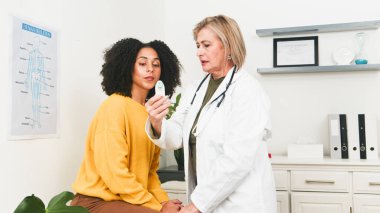 Beyaz önlüklü bir doktor, klinikteki hastayı muayene etmek için el bilgisayarı kullanır. Bakım, profesyonellik ve rutin bir sağlık kontrolü..