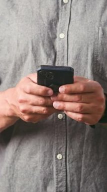 Modern bir akıllı telefonu tutan ve ustalıkla çalıştıran birinin yakın çekimi. Bireyler aktif olarak yazıyorlar, muhtemelen mesajlar gönderiyorlar, içeriğe göz atıyorlar veya mobil cihazda sosyal medyaya bağlanıyorlar..