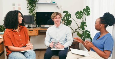 Modern bir ofiste yapılan sıradan bir takım toplantısında üç arkadaş fikir ve gülümseme paylaşıyor. Dizüstü bilgisayarlar, dizüstü bilgisayarlar ve yeşillik ortak bir çalışma ortamı yaratıyor..