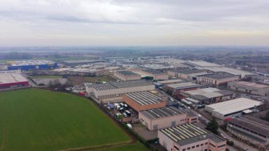 Hava görüntüleri, bulutlu gri gökyüzünün altında sayısız depo, fabrika ve lojistik merkezi bulunan geniş bir sanayi bölgesini yakalıyor.