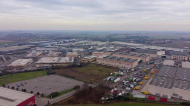 Çok sayıda deposu, fabrikası ve ticari binası olan büyük bir sanayi bölgesinin geniş hava manzarası. Birçok kamyonu olan bir lojistik merkezi.
