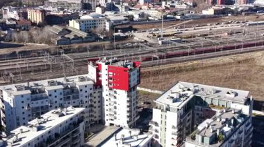 Büyük bir demiryolu yakınındaki modern bir apartmanın havadan görünüşü. Yüksek hızlı bir yolcu treni arka planda raylar boyunca seyahat eder.