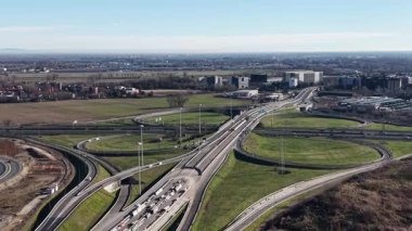 Güneşli bir günde birden fazla şerit, rampa ve üstgeçitte giden araba ve kamyonlarla karışık bir otoyol kavşağının yüksek açılı görüntüsü