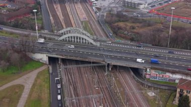 Şehir otoyolu trafiği köprünün üzerinden akıyor. Aşağıda birden fazla tren yolu var. Şehir altyapısı ve ulaşım ağının yüksek açılı perspektifi
