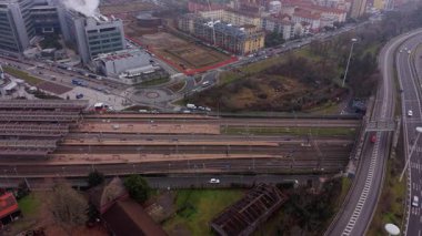 Yüksek açılı perspektif, bulutlu bir günde arabaların boş tren raylarının yanında çok şeritli bir otoyolda ilerlediğini gösteriyor.