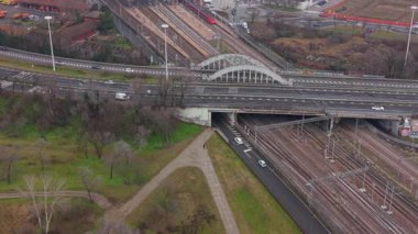 Hareketli bir ulaşım merkezinin yüksek açılı perspektifi üst geçitte araba trafiğini gösteriyor ve aşağıdaki demiryolunda yüksek hızlı bir tren var.