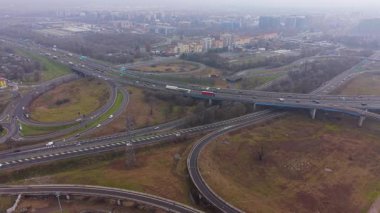 Köprüleri ve rampaları olan karmaşık bir otoyol kavşağının yüksek perspektifi. Araçlar ve kamyonlar yoğun kavşaktan geçiyor.