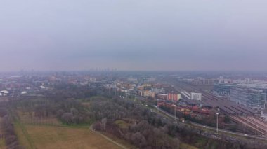 Sisli bir günde Avrupa şehir manzarasının kasvetli hava perspektifi. Otoyol trafiği yoğun ve parkın yanında büyük bir tren istasyonu var.