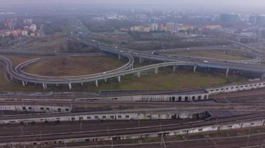 Sisli bir günde, yoğun bir karayolu kavşağını köprüler ve üstgeçitlerle gösteren hava aracı görüntüsü.