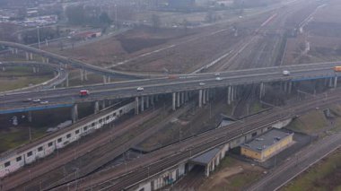 Çoklu tren rayları, demiryolu hatları ve hareket halindeki bir otoyol üst geçidi olan karmaşık bir ulaşım ağının havadan görüntüsü.