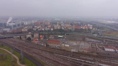 Endüstriyel bir şehrin kenar mahallelerindeki büyük bir demiryolu ağının havadan görüntüsü. Yayılan şehir manzarası sabah sisiyle örtülüdür.