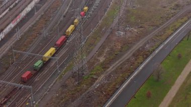 Renkli bir kargo treninin yüksek açılı perspektifi. Demiryolu boyunca ilerleyen konteynırlar bir yol kenarındaki sanayi bölgesinde.
