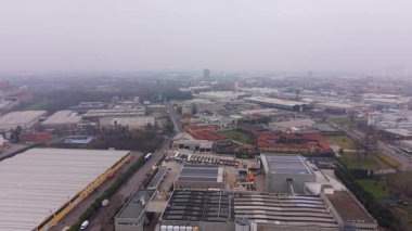 Çatılarda depo, fabrika ve güneş panelleri olan endüstriyel hava üssü kurulumu. Bulutlu bir günde şehrin banliyösünün panoramik görüntüsü