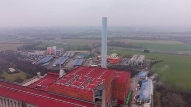 Büyük endüstriyel kompleksi, atmosfere buhar salan önemli bir baca yığını. Hava perspektifi fabrikanın düzenini gösteriyor.