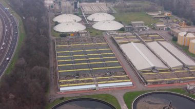 Dairesel yerleşim tankları ve arıtma havuzlarıyla endüstriyel atık su arıtma tesisi. Yoğun bir otoyolun yanındaki kanalizasyon tesisinin hava perspektifi