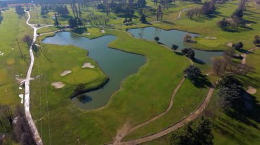 Gür yeşil golf sahasının güzel havadan bakış açısı. Kamera manikürlü çayırların, kum tuzaklarının ve büyük bir gölün üzerinde yavaşça döner.