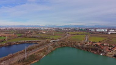 Şehir manzarası ve ufuktaki karlı alpler ile farklı renkte sulara sahip iki gölü ayıran demiryolu raylarının ideal hava perspektifi.
