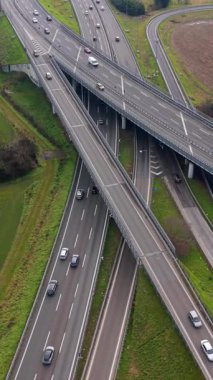 Yeşil kırsal kesimde üst geçitler ve rampalar arasında giden trafik ile çok katlı karmaşık bir otoyol kavşağının yukarıdan aşağıya havadan görüntüsü