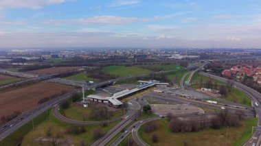Yüksek açılı insansız hava aracı, bulutlu bir günde kalabalık bir otoyol gişesi ve karmaşık yol kavşağında trafiğin akışını yakalıyor.