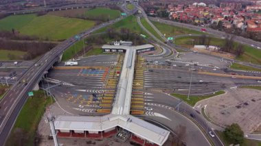 Yüksek açılı insansız hava aracı ana otoyoldaki bir gişede trafik akışını yakalıyor ve araçlar ödeme kapılarından geçiyor.
