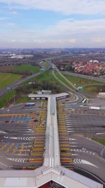 Büyük bir otoyolda, içinden arabalar ve kamyonlar geçen modern bir gişe kapısı. Ulaşım altyapısı ve karayolu ağının hava perspektifi
