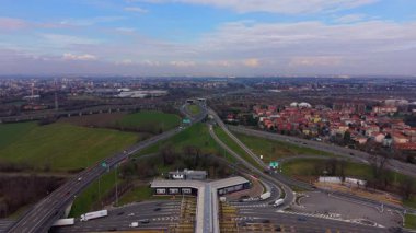 Yoğun bir otoyol gişesinin hava perspektifi ve oradan geçen araçlar. Otomobiller ve kamyonlar yol kavşağında ve şebekede