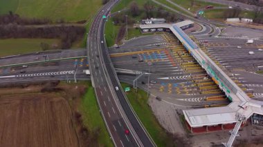Yoğun bir otoyol gişesinden geçen arabalar ve kamyonlar. Ödeme engelinde altyapı ve trafik akışını gösteren hava perspektifi