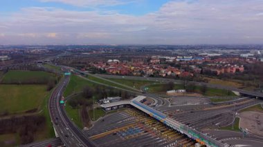 Yüksek açılı insansız hava aracı, kalabalık bir otobandan geçen arabaları yakalıyor. Uzaktan geniş bir şehir manzarası var.