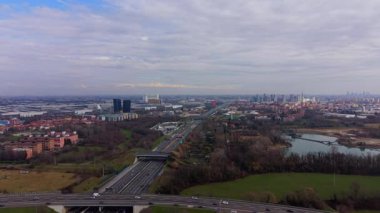 İtalya 'nın modern kenti Milan' a doğru giden araba ve kamyonları gösteren hava görüntüleri. Binalar ve doğa içeren şehir manzarası