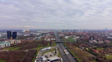 Geniş hava görüntüleri, bulutlu bir günde A4 karayolunun Milan siluetine çıktığını gösteriyor. Araç akışını ve kentsel yayılmayı yakalıyor.