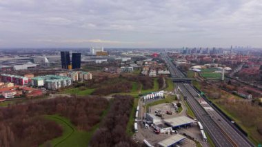 Milano, İtalya 'nın modern siluetine doğru akan çok şeritli bir otoyolun geniş hava manzarası bulutlu bir gökyüzünün altında.