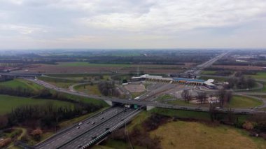 Çoklu şeritli bir otoyolda kalabalık bir gişenin panoramik hava görüntüsü. Ödeme istasyonundan geçen arabalar ve kamyonlar.