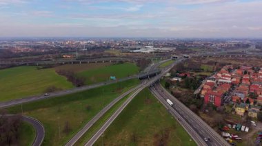 Viyadük ve üstgeçitlerle modern bir otoyol kavşağının insansız hava aracı görüntüleri. Araçlar ve kamyonlar bir şehrin yakınındaki otoyol boyunca ilerliyorlar.