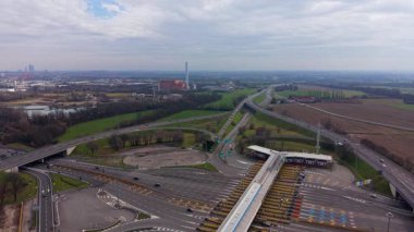 Hava aracı görüntüleri otoyol gişelerinden birine yaklaştığını gösteriyor. Karmaşık yollar, üstgeçitler ve şehrin yakınında bir kavşak.