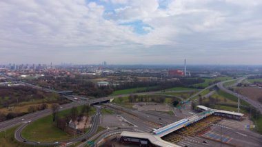 Hava görüntüsü otoyol gişelerinden geçen arabaları gösteriyor. Geniş bir yol ağı ve Milano 'nun ufuk çizgisiyle uzaktan görülebilen kavşaklar