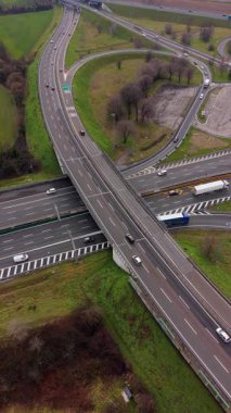 Üstgeçit ve akan trafik ile bir otoyol kavşağının havadan görüntüsü. Asfalt yollarda seyahat eden arabalar, kamyonlar ve otobüsler.