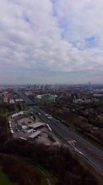 Hava aracı görüntüleri, Milan, İtalya 'nın modern siluetine doğru giden çok şeritli bir otoyolda bulutlu bir gökyüzünün altında yoğun trafiği gösteriyor.