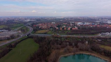 Yüksek açılı insansız hava aracı, banliyöde küçük bir göl ve ulaşım ve altyapıyı gösteren yoğun bir otoyol kavşağını yakalıyor.