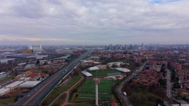 Milan, İtalya 'nın geniş hava manzarası. Şehrin modern siluetine doğru uzanan yoğun bir otoyol bulutlu bir gökyüzünün altında.