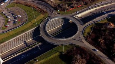 Büyük bir otoyolun üzerinde karmaşık bir döner kavşakta giden araçların yüksek açılı drone görüntüleri. Modern mühendislik ve karayolu altyapısı