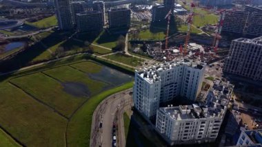 Üst-alt hava manzarası yeşil tarım alanı ile modern yerleşim bölgesi arasındaki karşıtlığı gösteriyor.